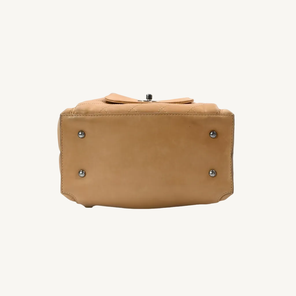 Tan leather handbag with silver studs on a white background