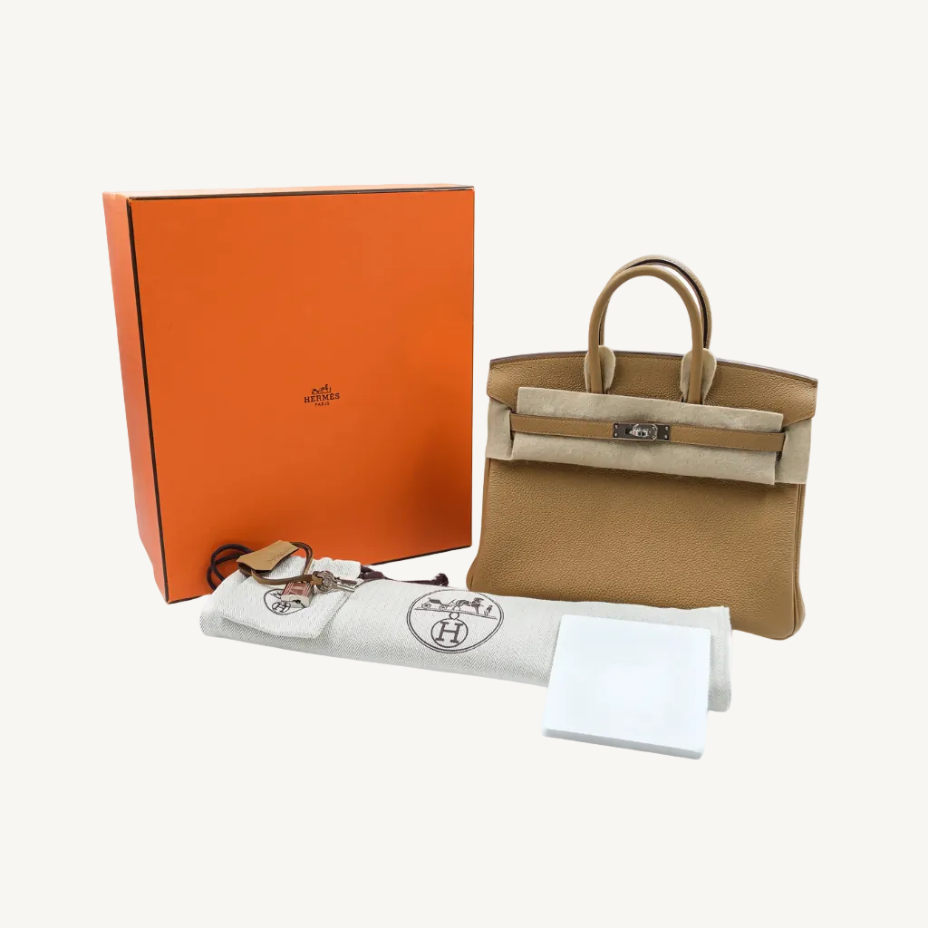 Brown handbag with orange box, keychain, and papers on a white background